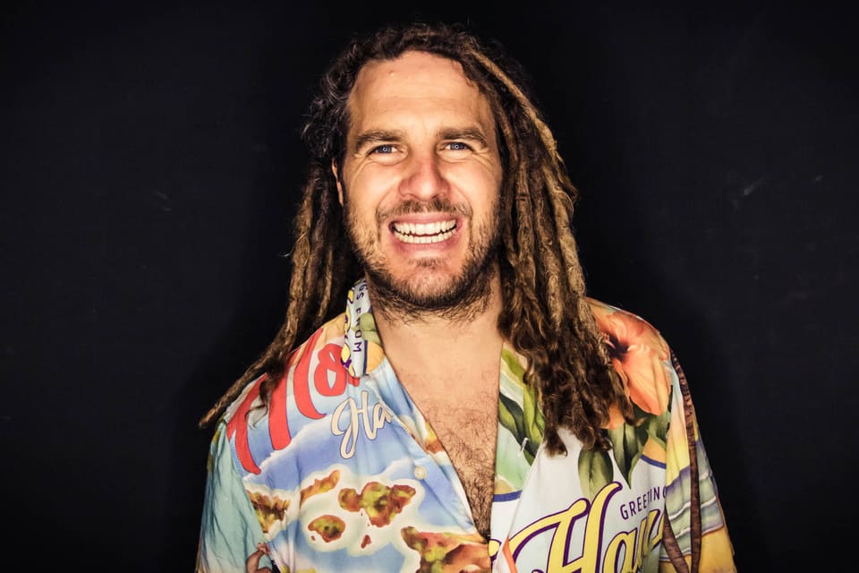 Daniel Fetzy Fetz lächelt im bunten Hawaiihemd vor schwarzem Hintergrund