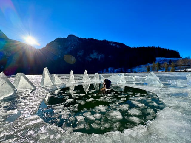 Eisbadender in einem sonnigen Eisloch am zugefrorenen Gleinkersee