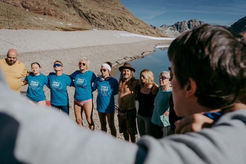 Retreatgruppe steht gemeinsam im Kreis am Bergsee im Pitztal