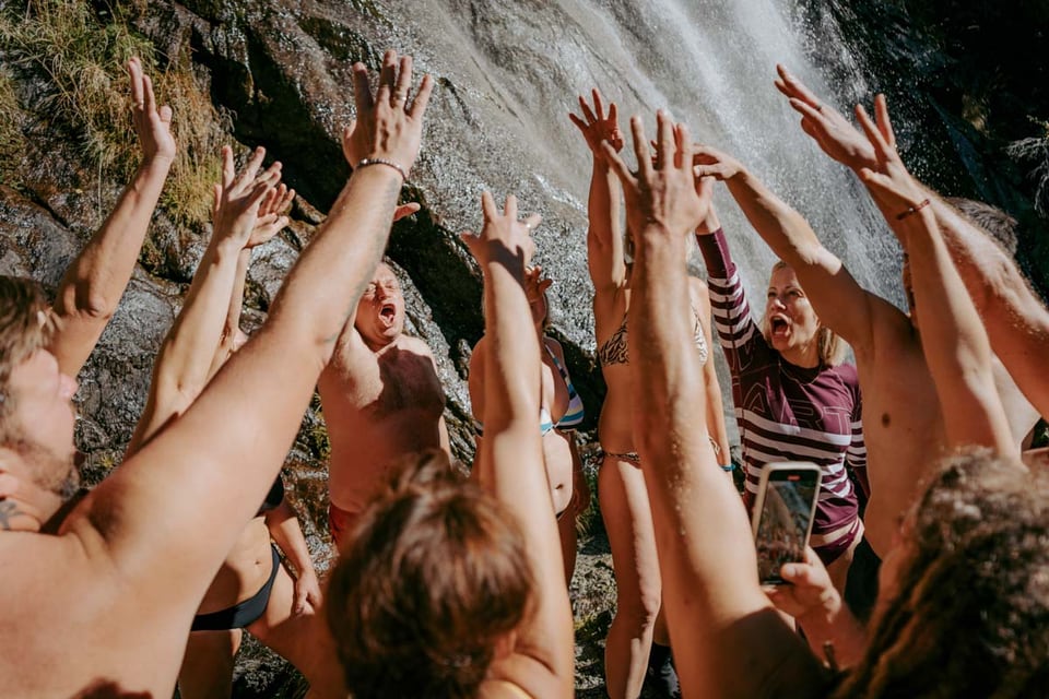 Retreatgruppe jubelt nach dem Eisbad an einem Wasserfall