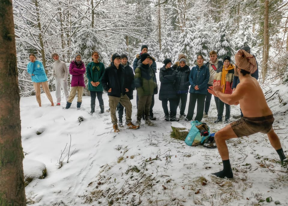 Jugendliche beobachten eine Aufwärmübung im verschneiten Wald