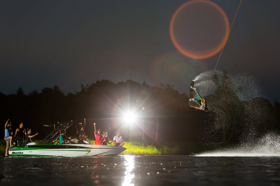 Daniel Fetzy Fetz springt nachts mit dem Wakeboard hinter einem beleuchteten Boot